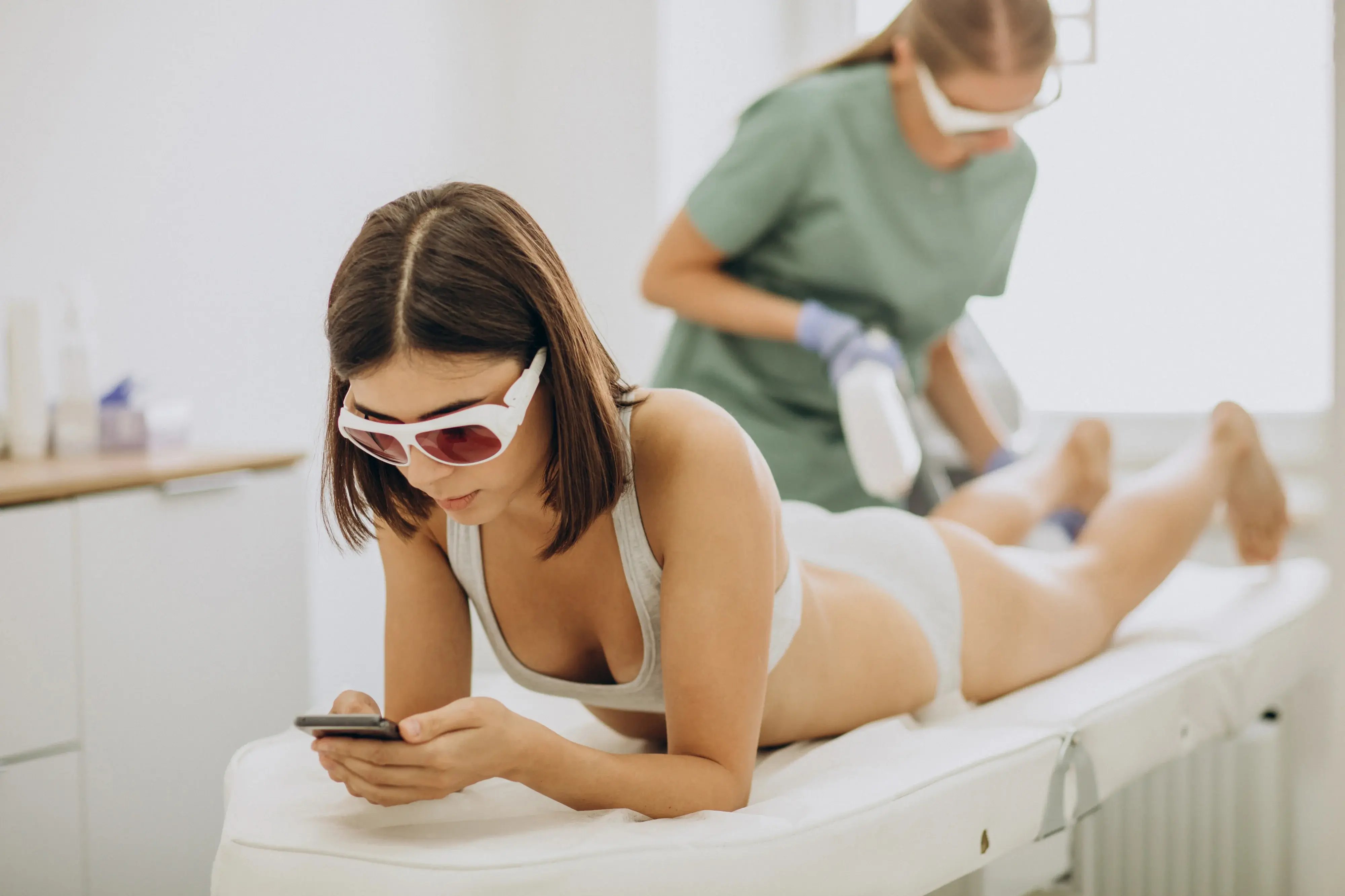 Women on phone during brazilian laser treatment