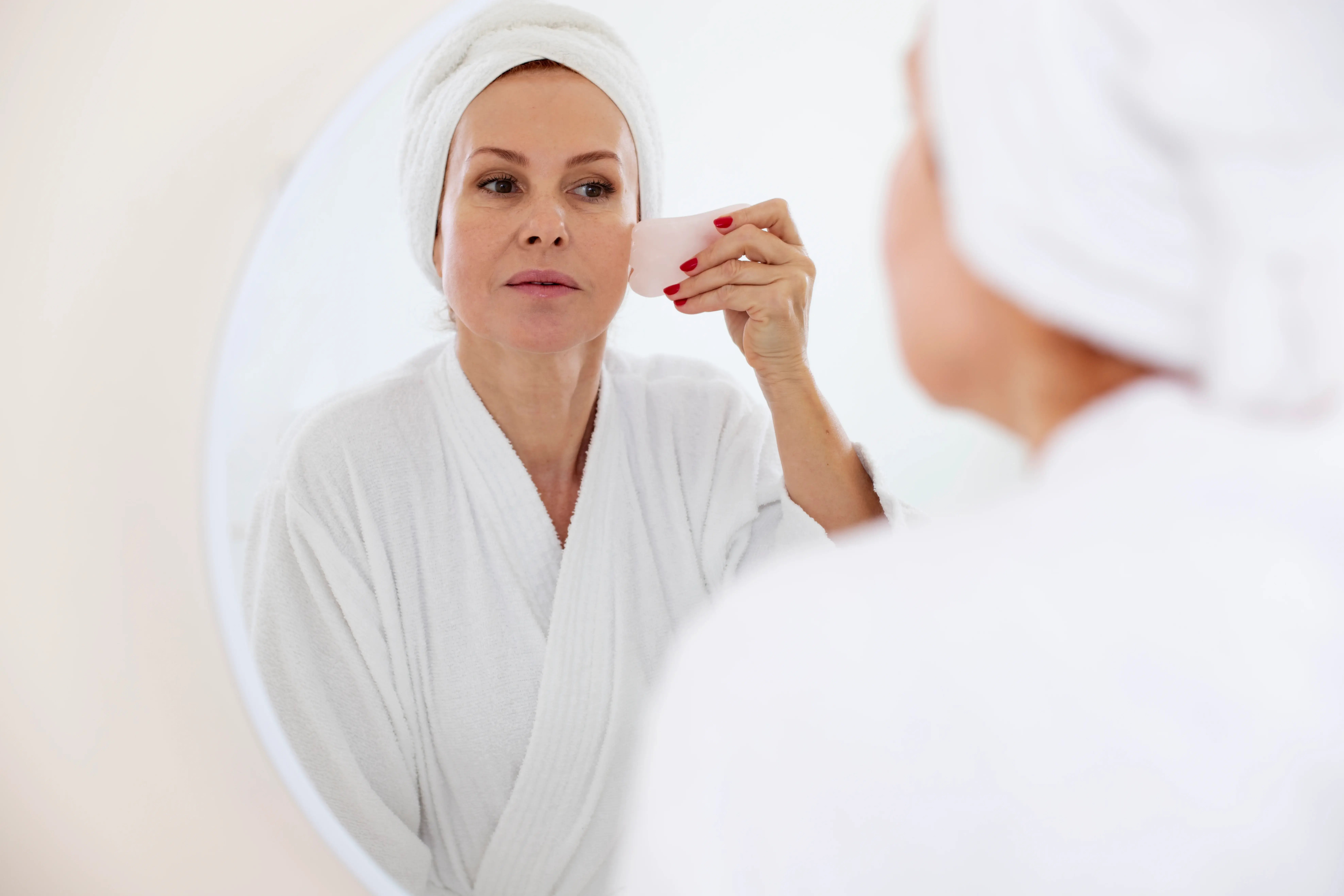 women in robe prepping face for medical skincare routine